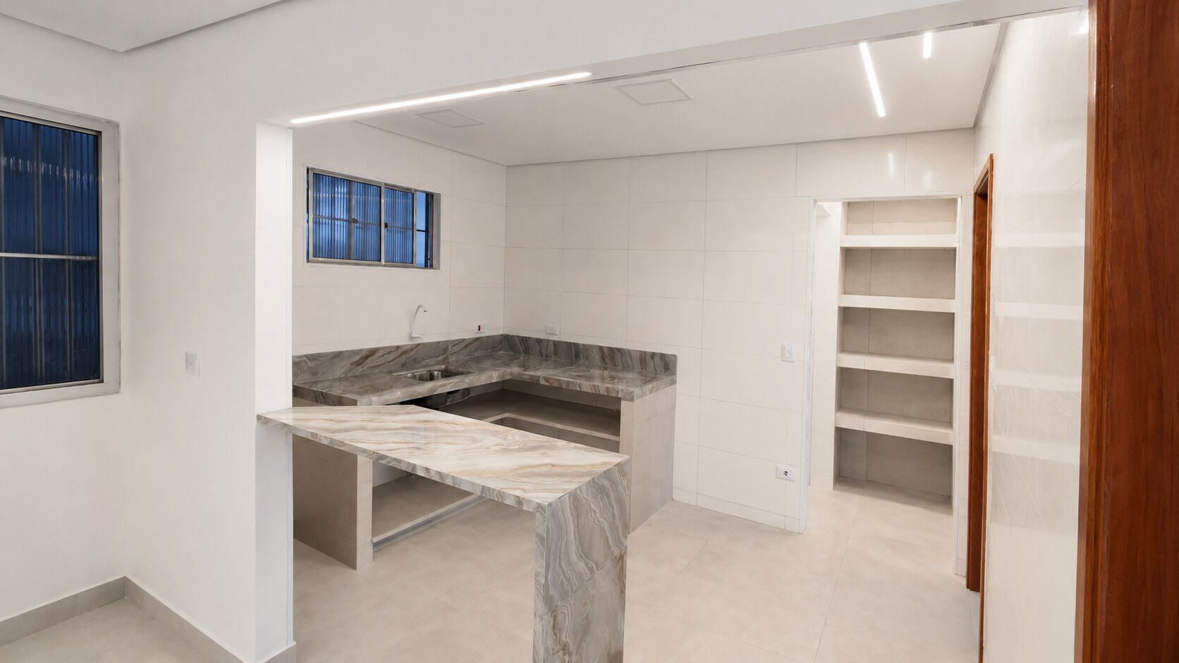 Cozinha em execução com bancadas de pedra e iluminação linear